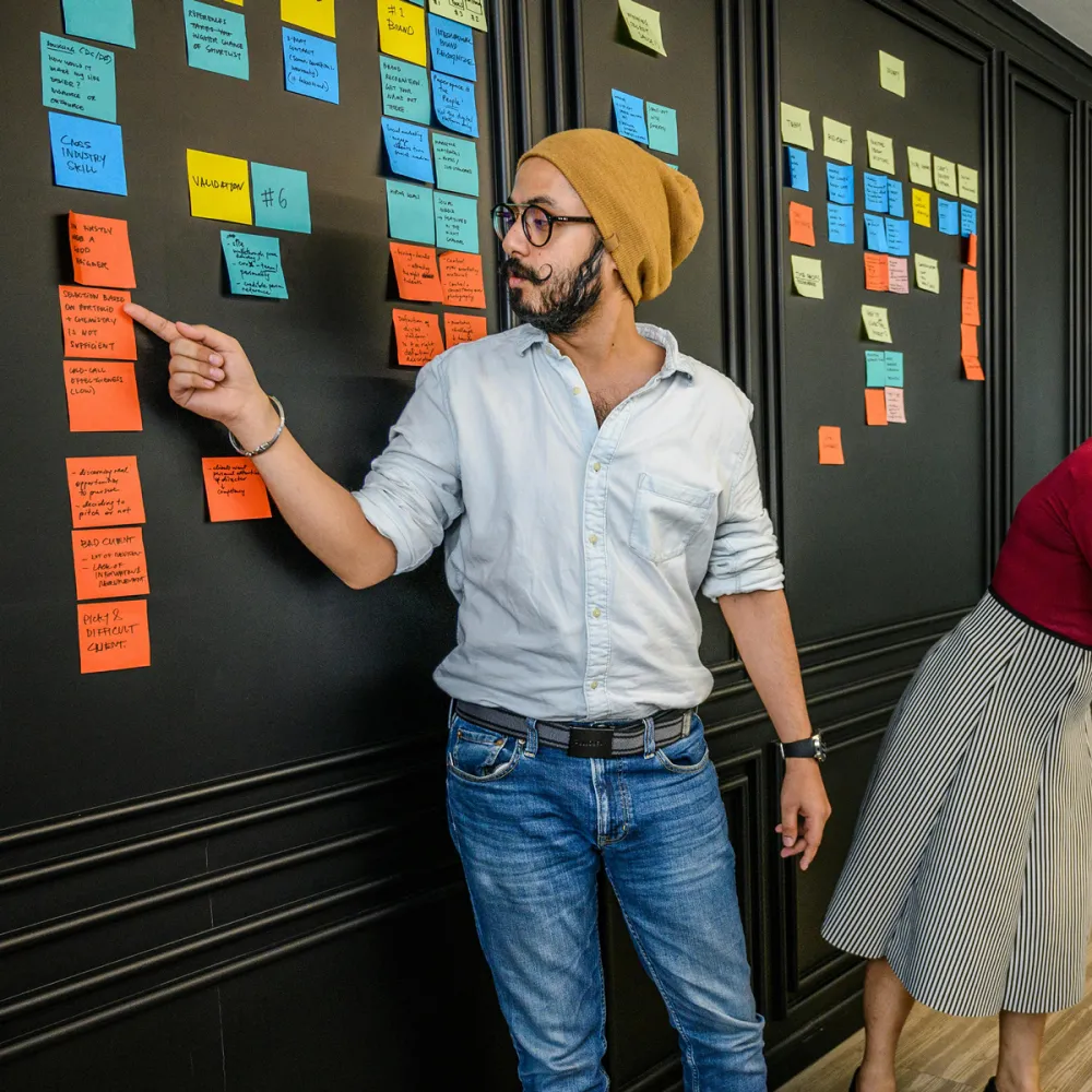 Man standing next to a board full of sticky notes to prioritise planning Man standing next to a board full of sticky notes to prioritise planning
