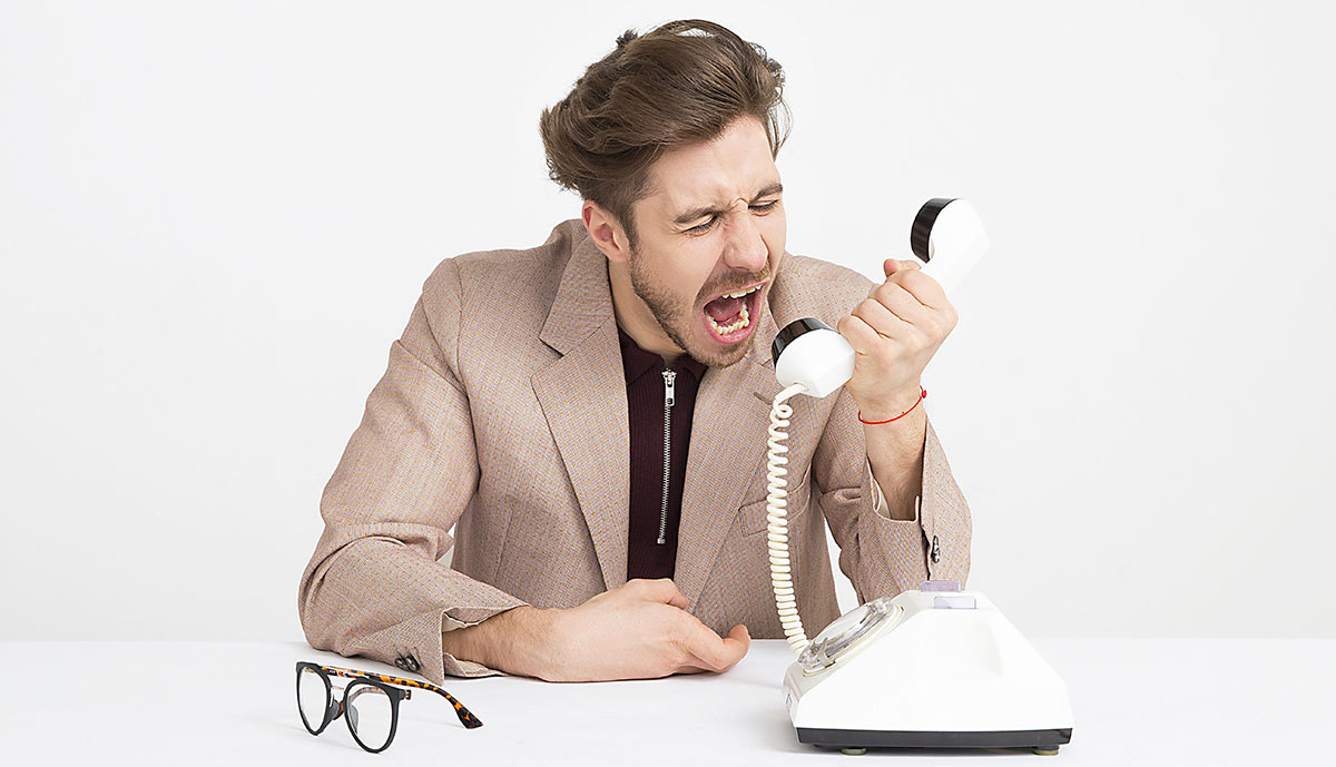 Man angry on the phone, dealing with traditional customer services rather than being able to solve it himself.
